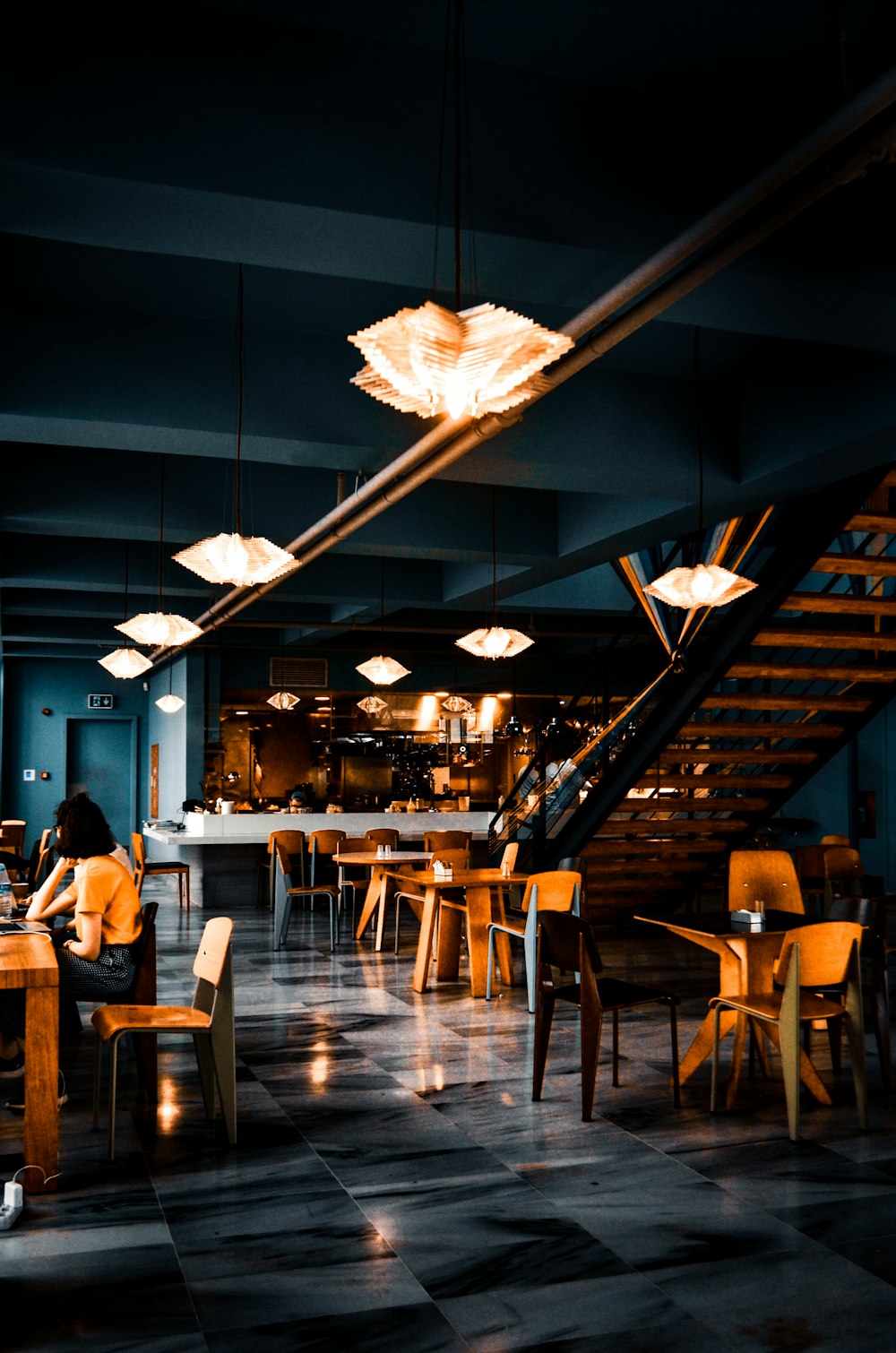 Moody restaurant interior with paper lantern lighting and a wooden staircase
