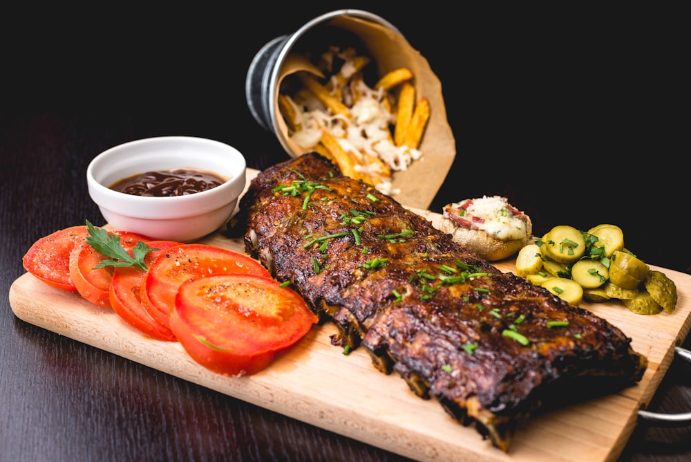 Wood-fired ribs plated on a board with charred vegetables